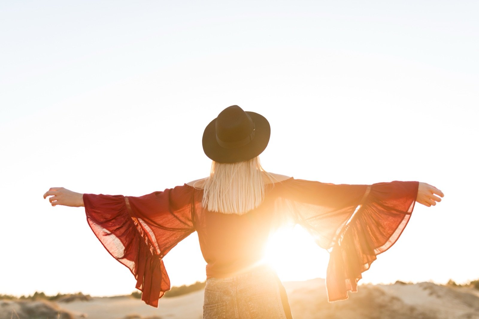 A woman with her arms open toward the horizon at sunrise