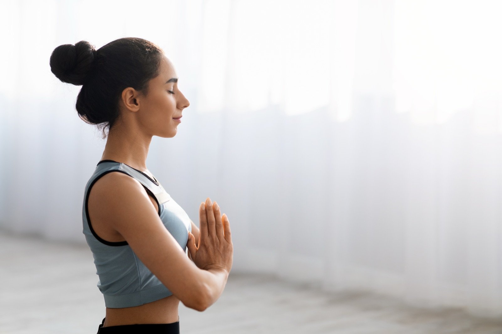 A woman meditating at home in natural light