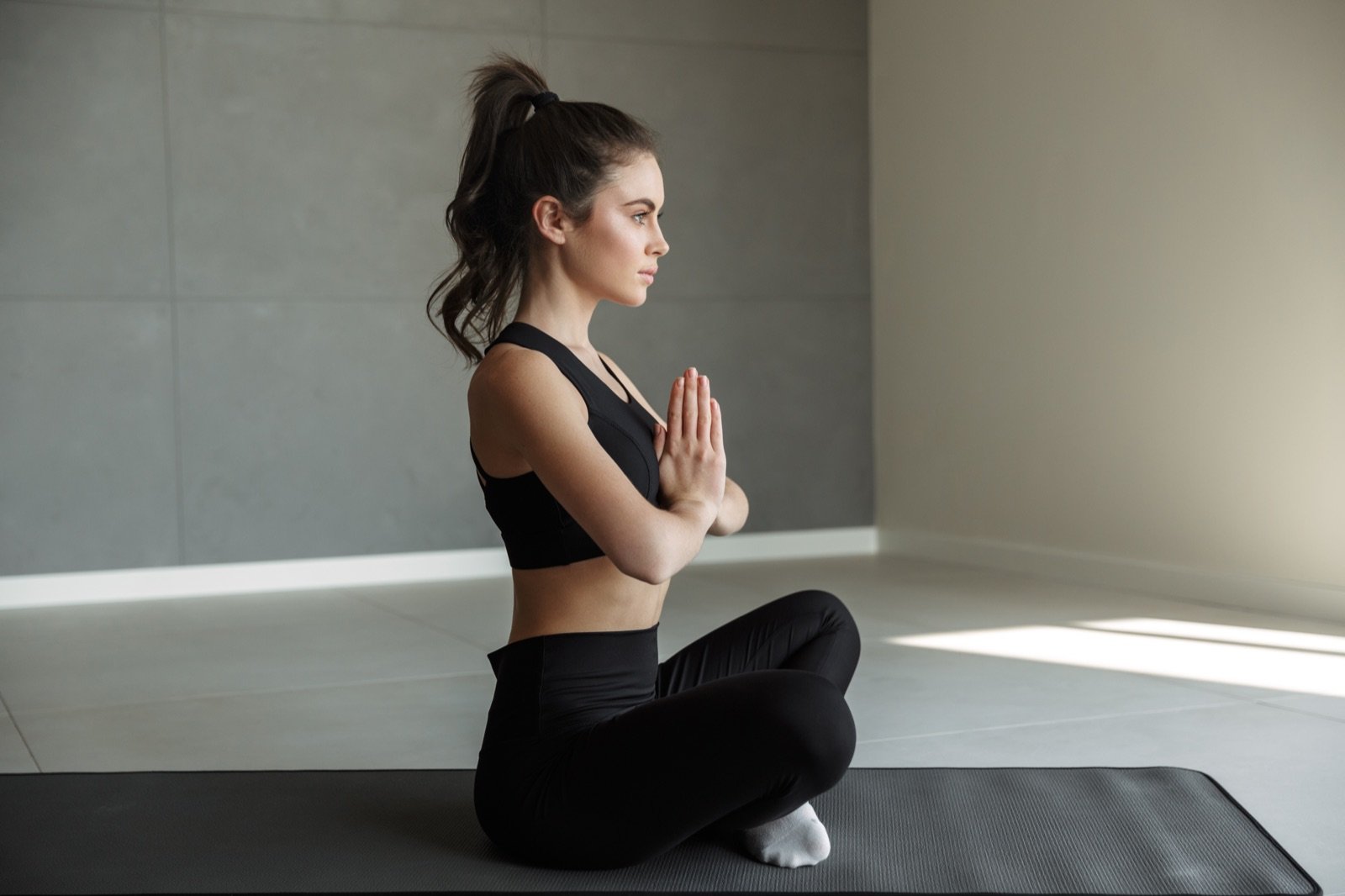 A woman sitting quietly on a mat in natural light